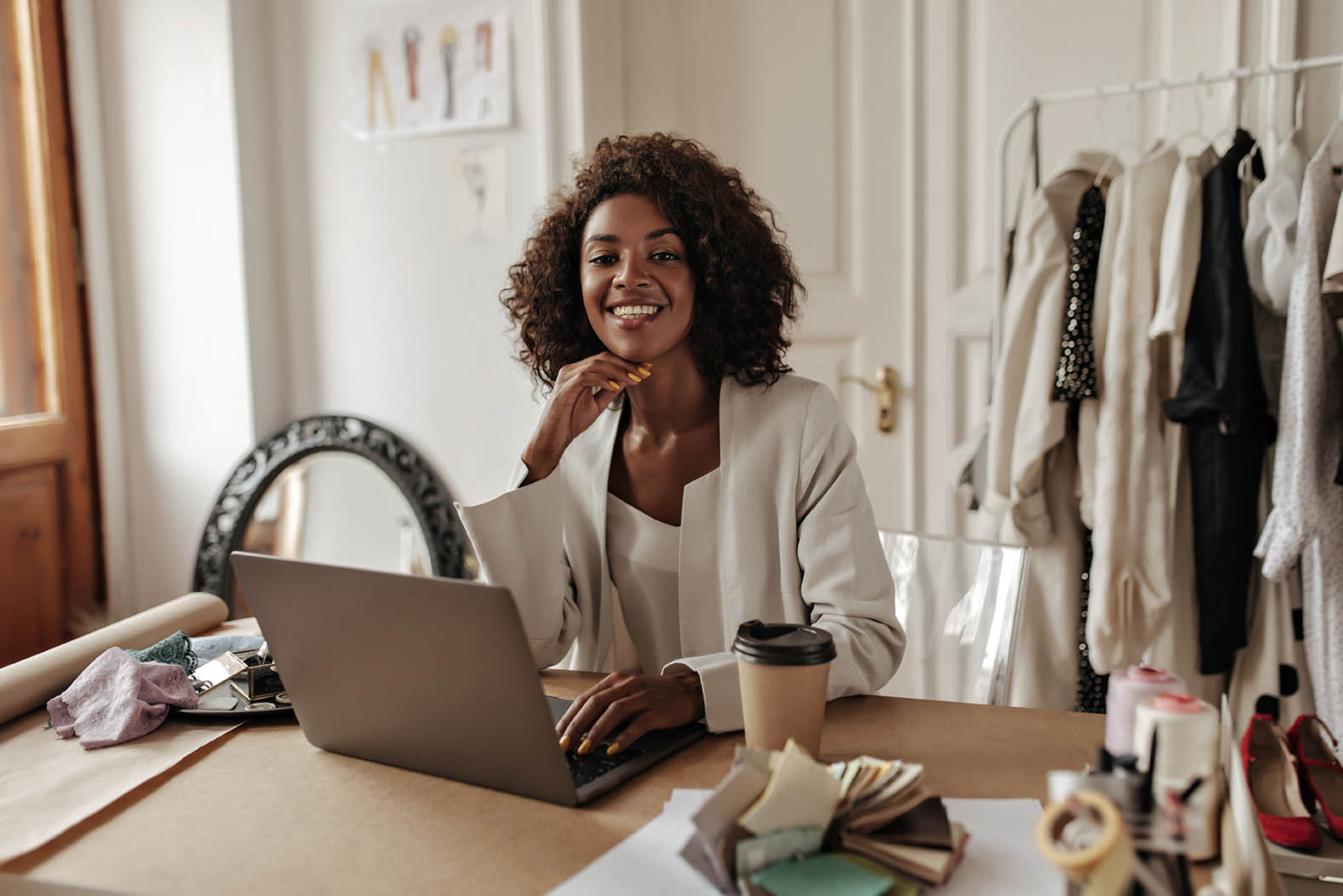 skinned_woman_stylish_jacket_blouse_smiles_looks_camera_works_laptop_poses_office